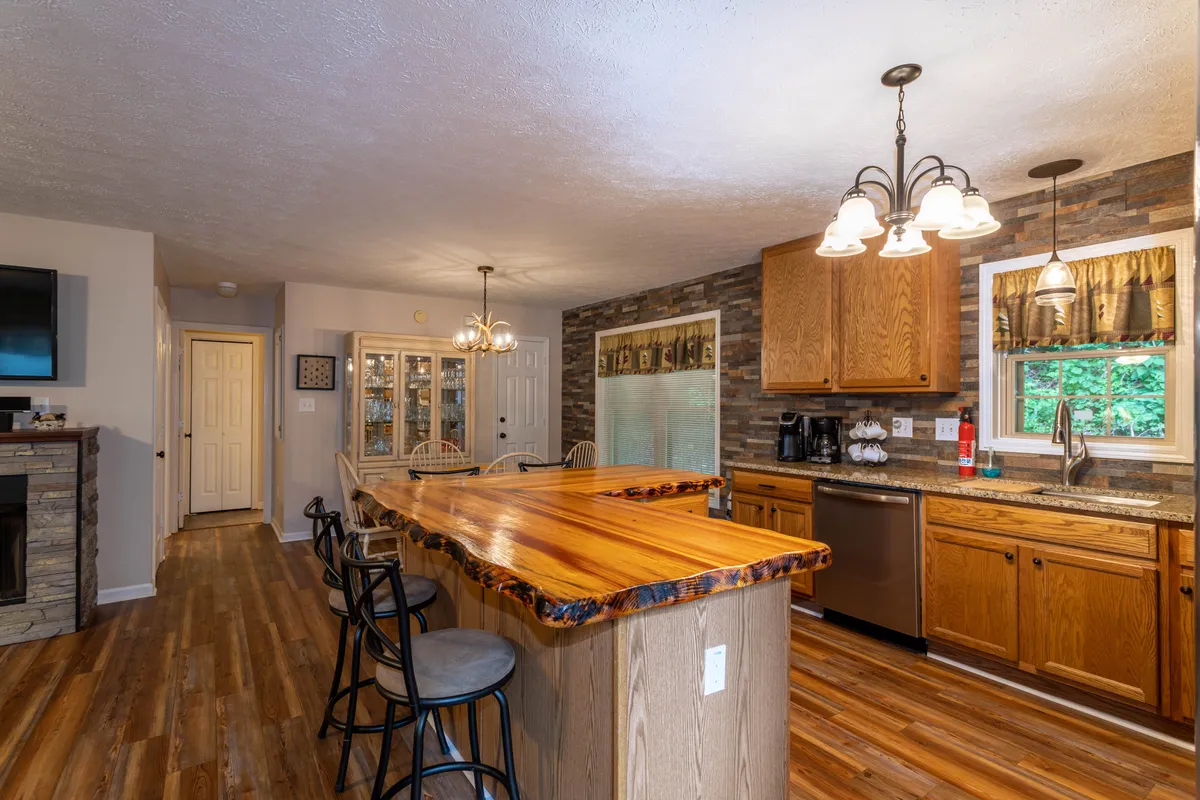 A spacious kitchen and dining area with a large wooden island, stone fireplace, and glass-front cabinets. The open layout encourages interaction, meal preparation, and shared experiences, complementing the sense of togetherness and convenience described in the section.