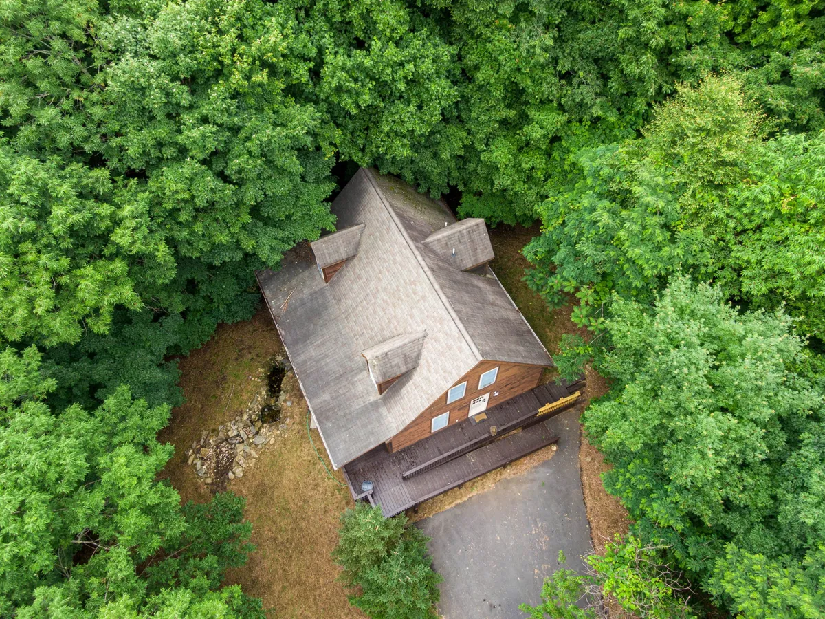 Another exterior perspective of the wooden house, focusing on the surrounding forest and serene atmosphere. The driveway hints at easy arrival and departure for day trips, while the trees reinforce the home’s close connection to nature and nearby trails.